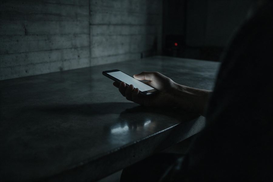 Consulta de un cliente por mensajería desde un teléfono, en penumbra.