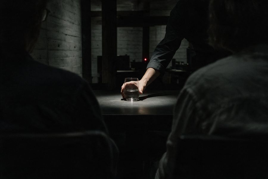 Servicio de mesa a dos huéspedes en un salón en penumbra.